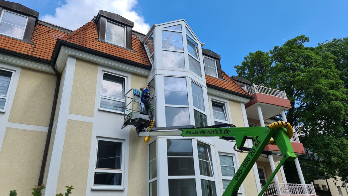 Hier wird gezeigt, wie die Außenverglasung mit einem Steiger in höherer Lage geputzt wird.
